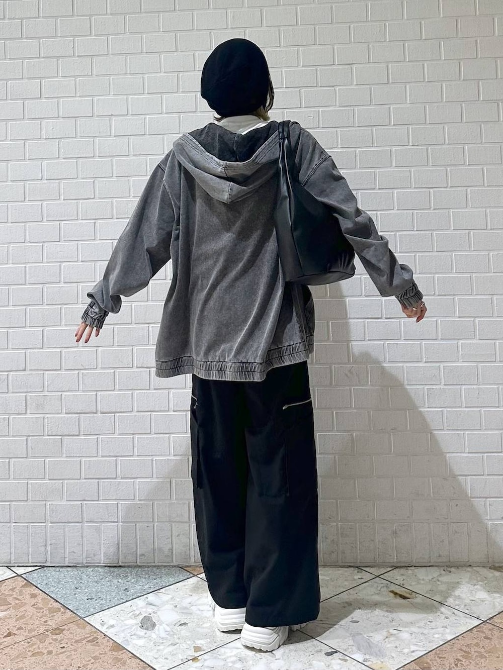 ホワイト系のスニーカー、ブラック系のスラックス、ブラック系のパーカーを着用したレディースの春コーディネートの7枚目の写真