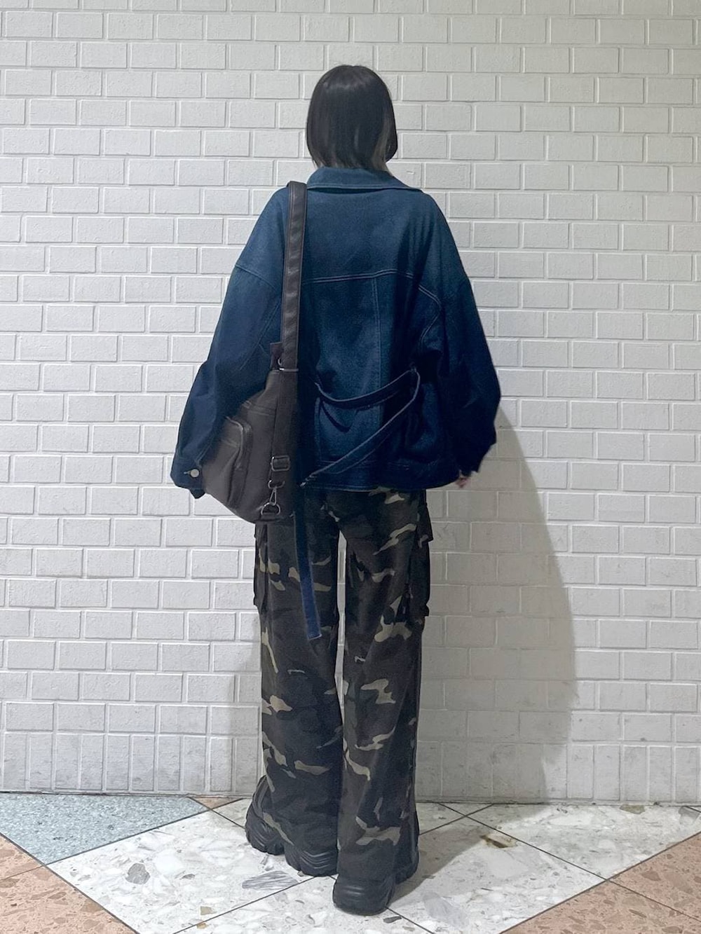 ブラウン系のブーツ、ブラック系のキャミソール、ブルー系のブルゾンを着用したレディースの春コーディネートの6枚目の写真