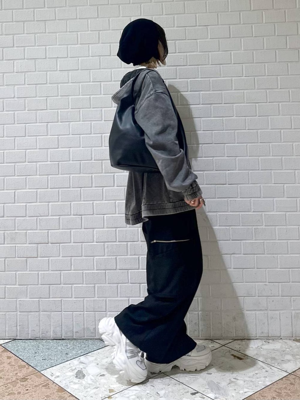 ホワイト系のスニーカー、ブラック系のスラックス、ブラック系のパーカーを着用したレディースの春コーディネートの8枚目の写真