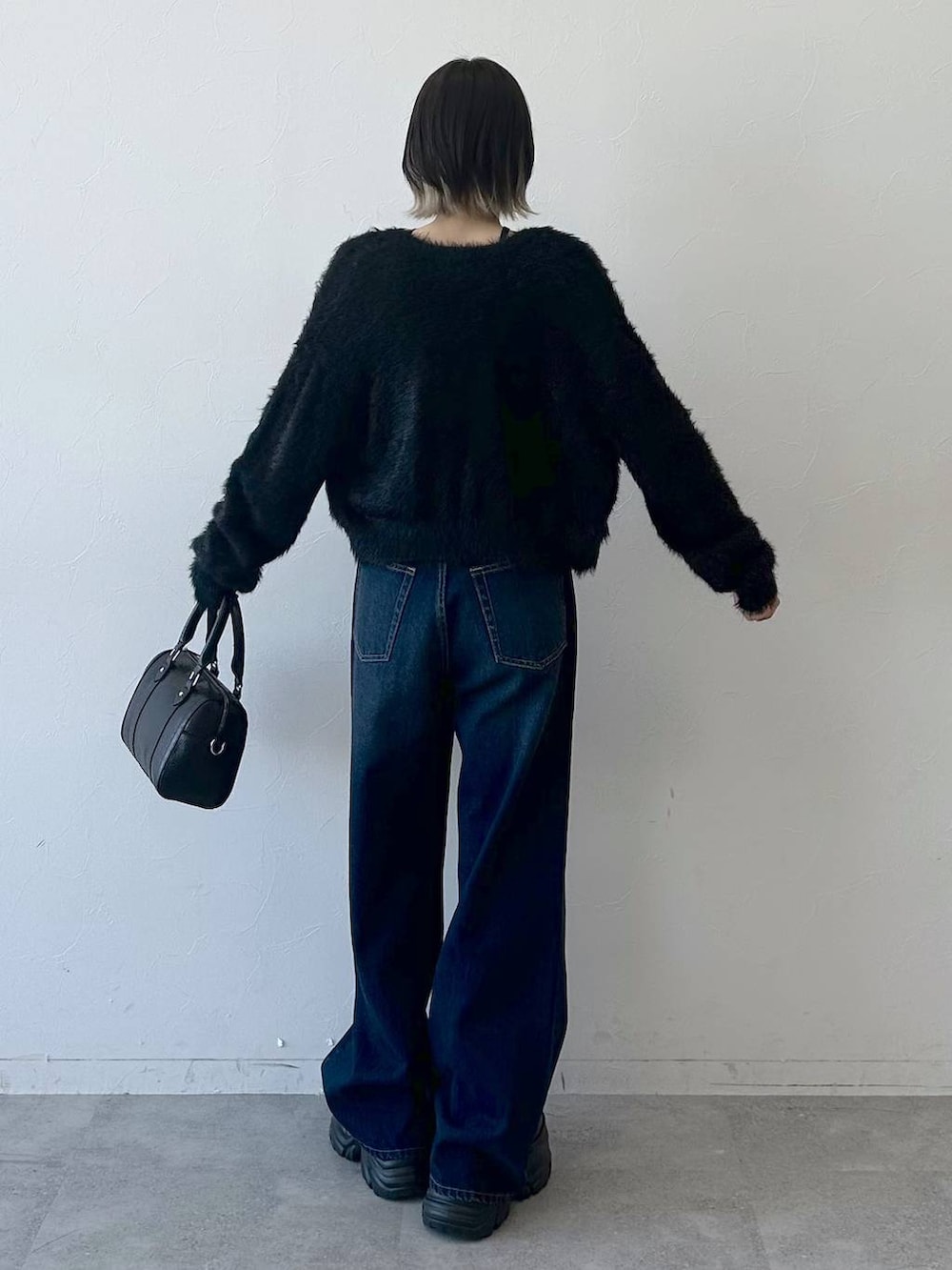 ブラック系のブーツ、ブルー系のスラックス、ブラック系のボストンバッグを着用したレディースの冬コーディネートの6枚目の写真