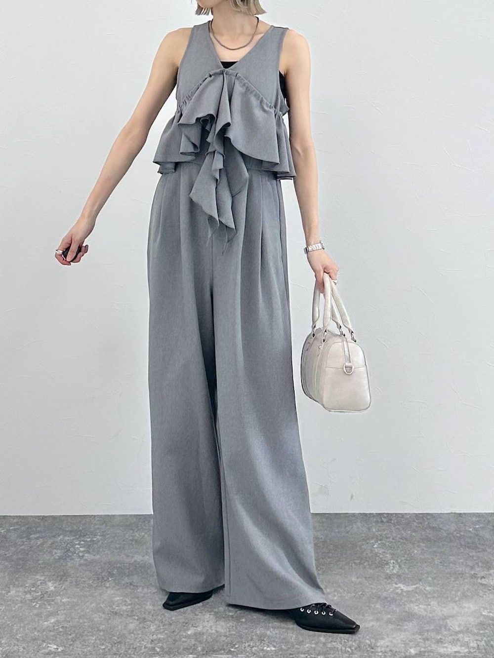 ホワイト系のボストンバッグ、ブラック系のサンダル、グレー系のサロペット/オーバーオールを着用したレディースの春コーディネートの2枚目の写真