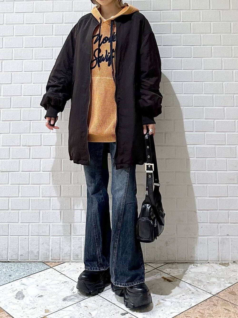 ブラック系のブーツ、ブルー系のデニムパンツ、ブラウン系のブルゾンを着用したレディースの秋コーディネートの2枚目の写真