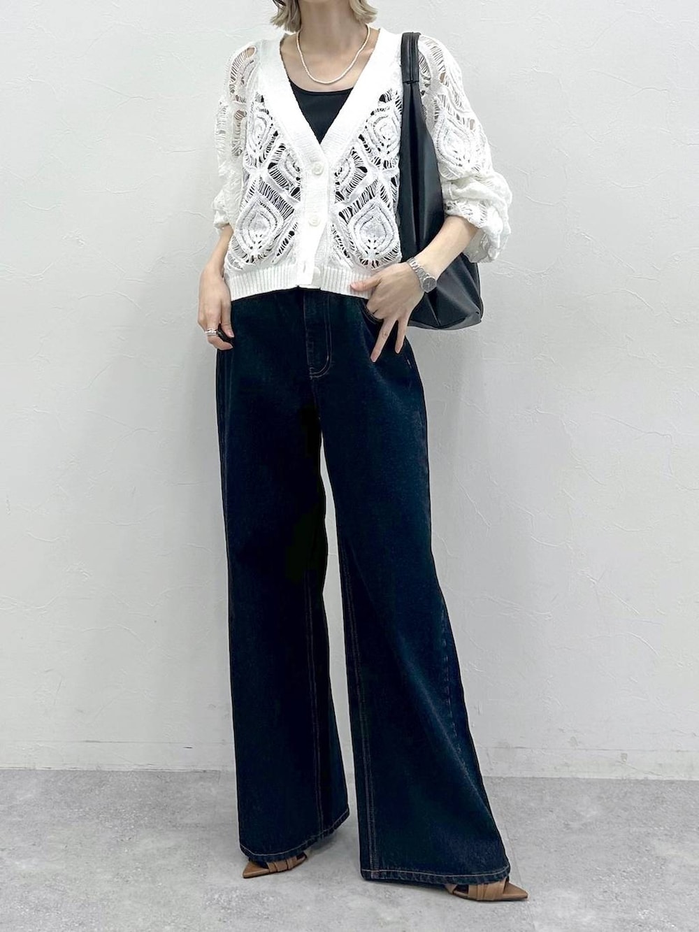 ブラック系のキャミソール、ホワイト系のカーディガン/ボレロ、ブルー系のスラックスを着用したレディースの春コーディネートの2枚目の写真