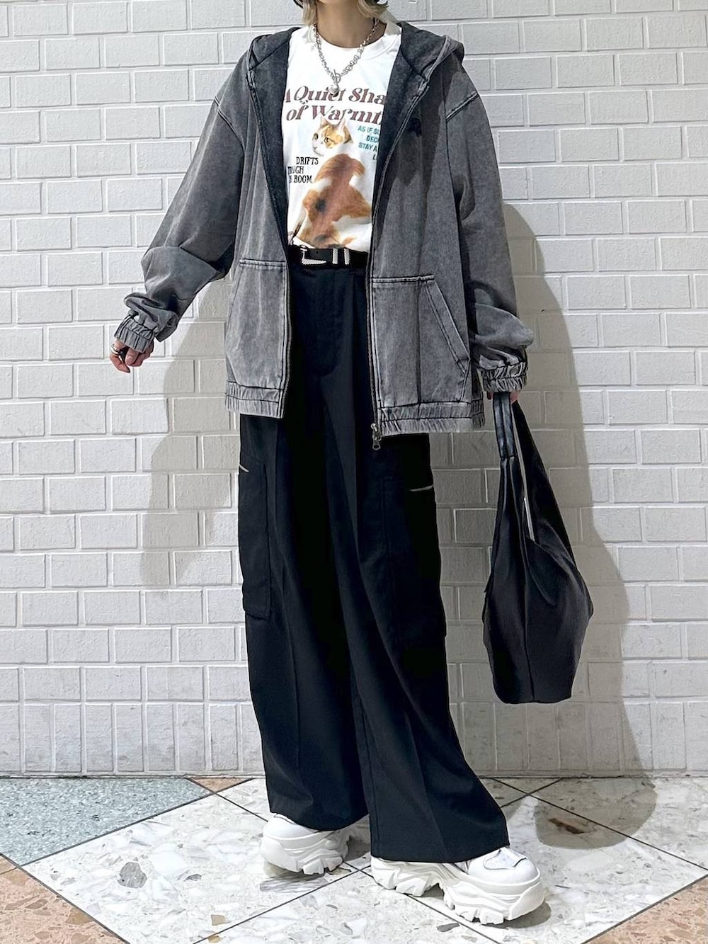 ホワイト系のスニーカー、ブラック系のスラックス、ブラック系のパーカーを着用したレディースの春コーディネートの4枚目の写真