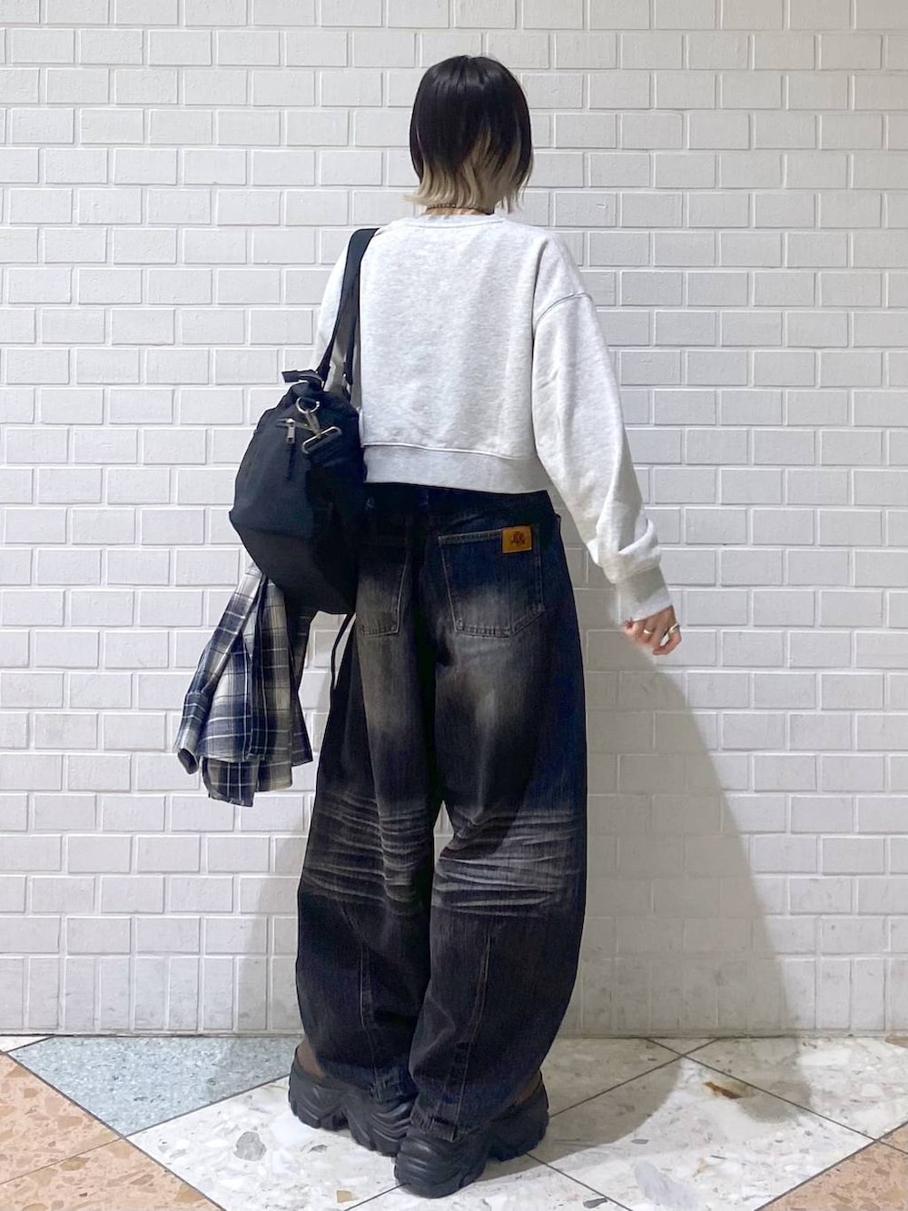 ブラウン系のブーツ、ブラック系のボストンバッグ、ブラック系のデニムパンツを着用したレディースの秋コーディネートの7枚目の写真