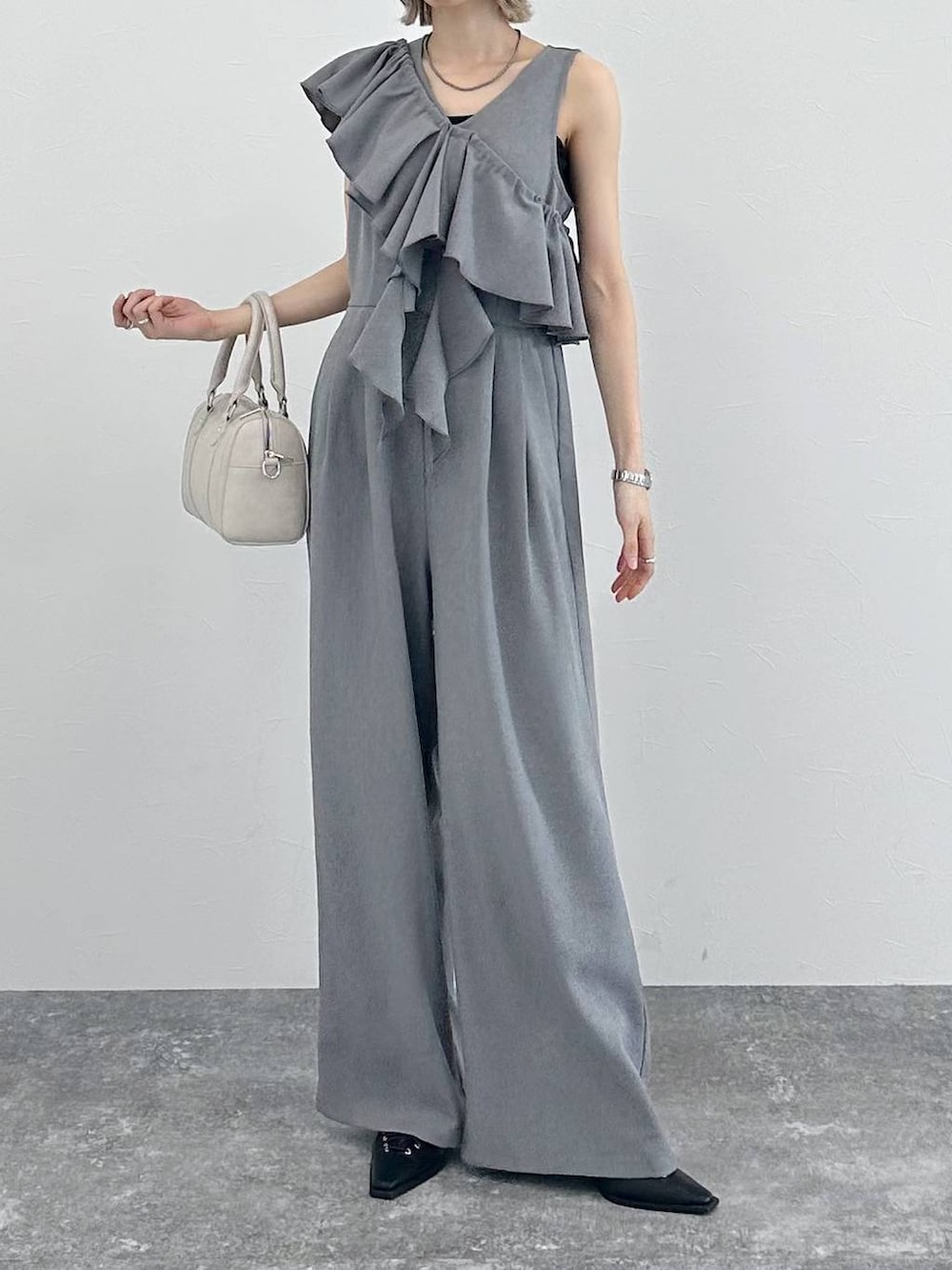 ホワイト系のボストンバッグ、ブラック系のサンダル、グレー系のサロペット/オーバーオールを着用したレディースの春コーディネートの5枚目の写真