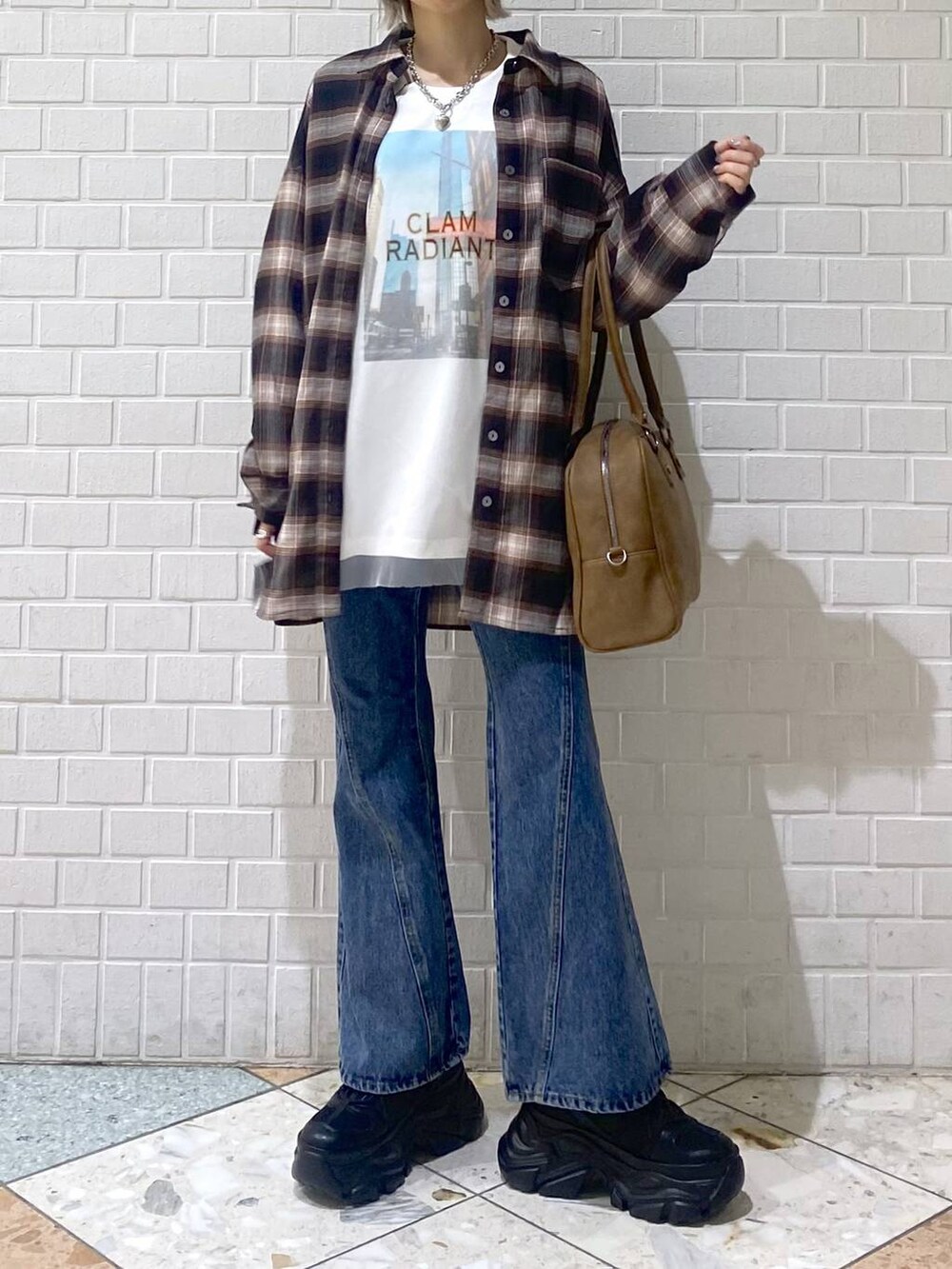 ブラック系のスニーカー、イエロー系のボストンバッグ、ブルー系のデニムパンツを着用したレディースの秋コーディネートの3枚目の写真