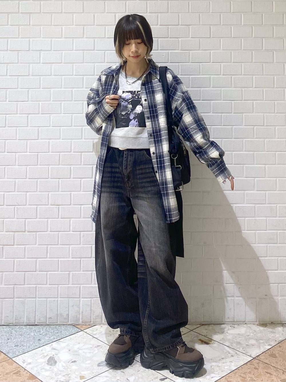 ブラウン系のブーツ、ブラック系のボストンバッグ、ブラック系のデニムパンツを着用したレディースの秋コーディネートの2枚目の写真