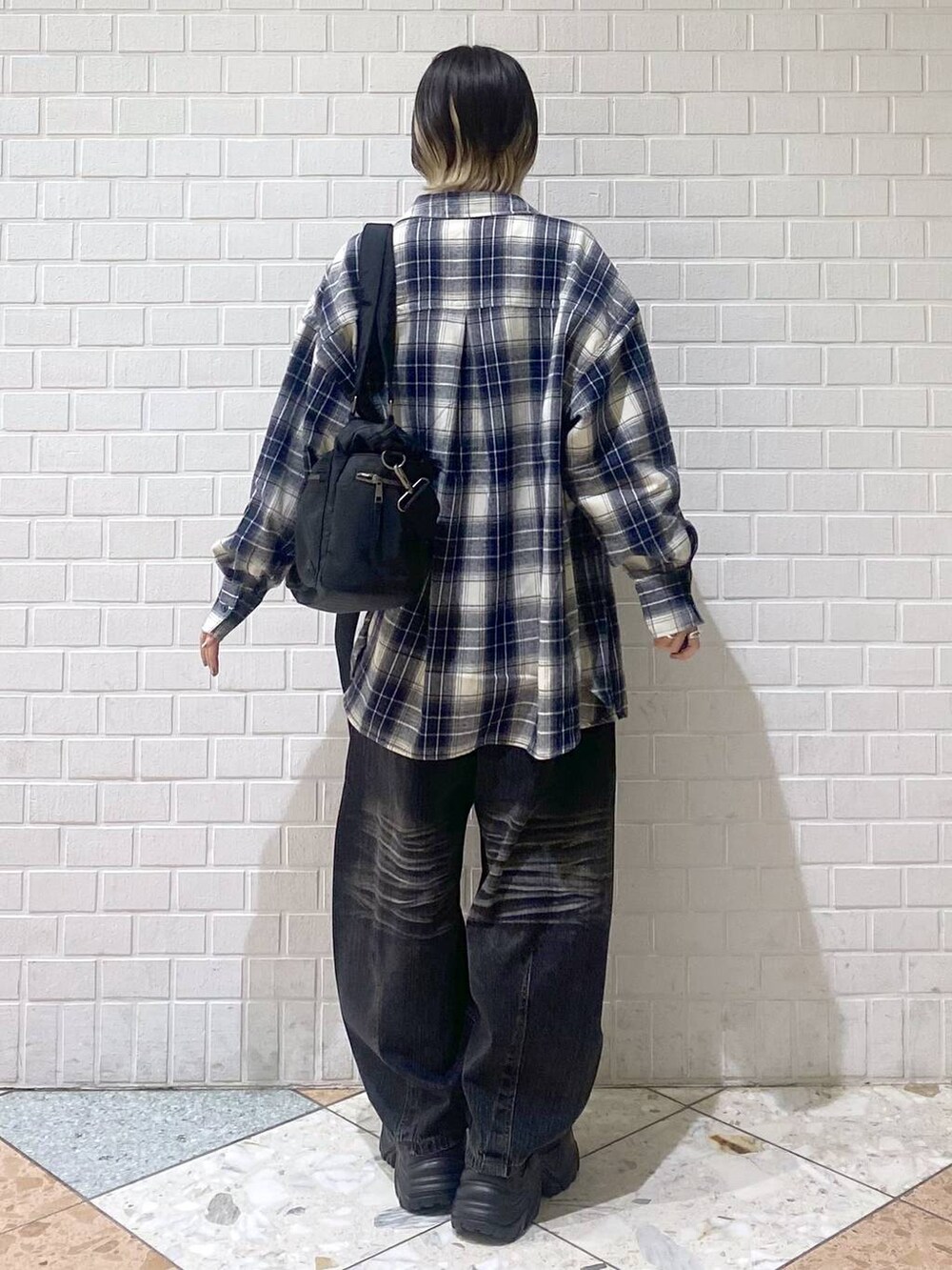 ブラウン系のブーツ、ブラック系のボストンバッグ、ブラック系のデニムパンツを着用したレディースの秋コーディネートの6枚目の写真