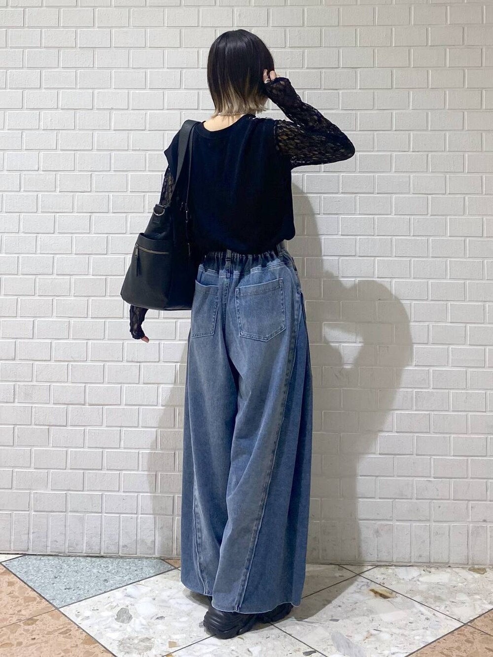 ブラウン系のブーツ、ブルー系のデニムパンツ、ブラック系のボストンバッグを着用したレディースの夏コーディネートの5枚目の写真