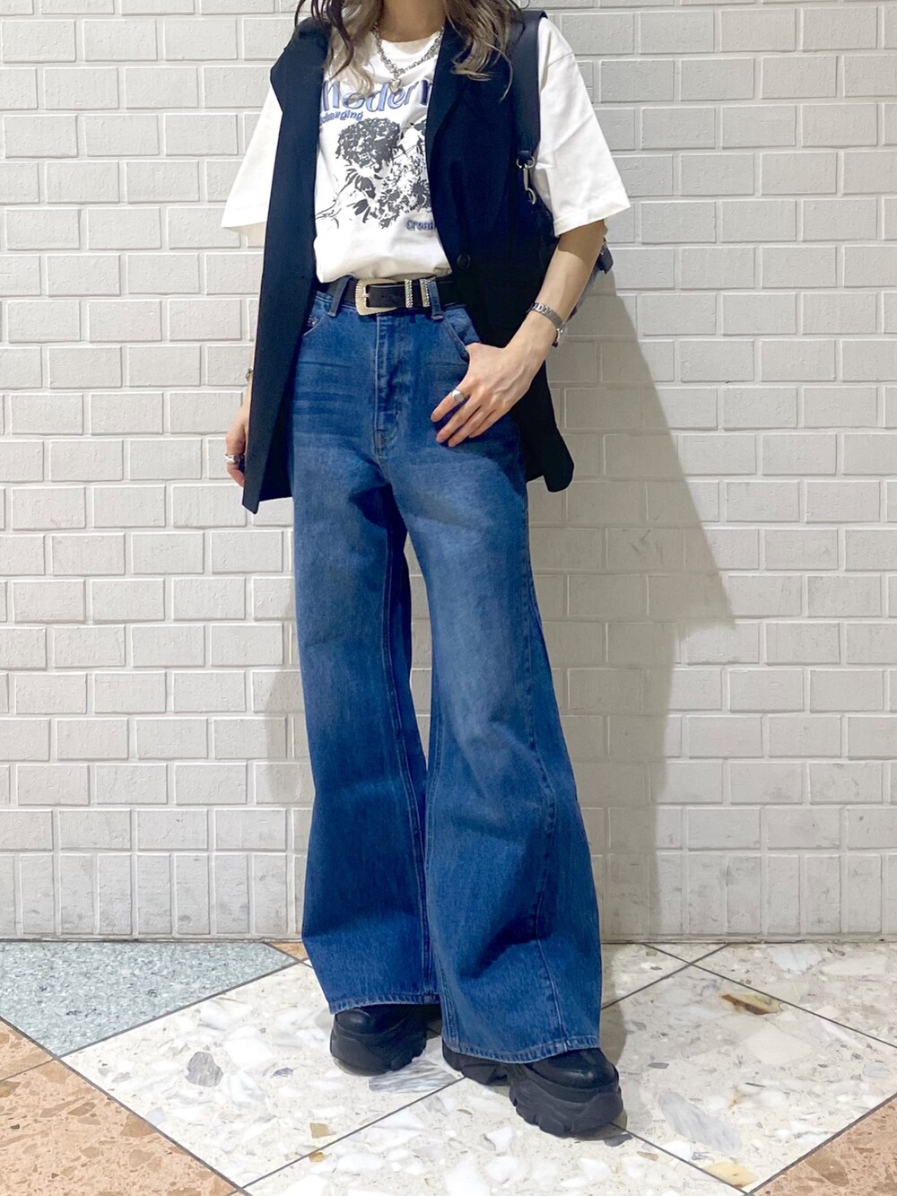 ブルー系のデニムパンツ、ブラック系のスニーカー、ブラック系のショルダーバッグを着用したレディースの秋コーディネートの5枚目の写真