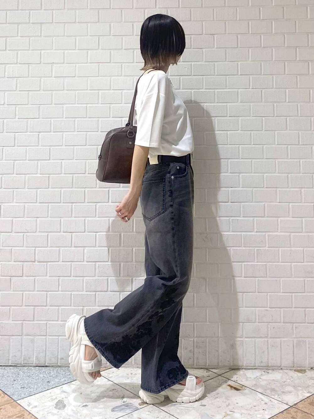 ブラウン系のボストンバッグ、ホワイト系のサンダル、ブラック系のデニムパンツを着用したレディースの春コーディネートの5枚目の写真