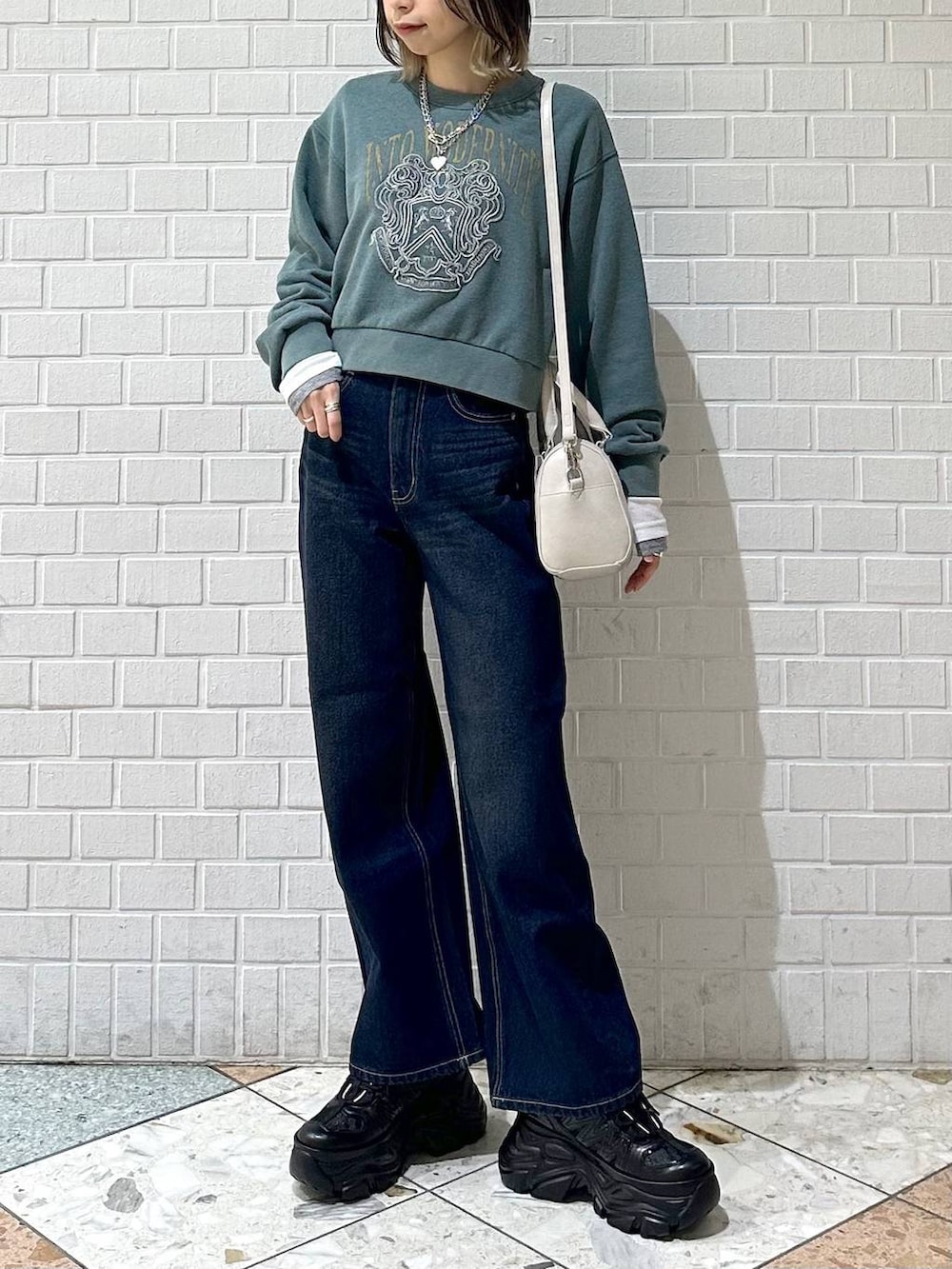 ブラック系のスニーカー、ブルー系のスラックス、ホワイト系のボストンバッグを着用したレディースの冬コーディネートの3枚目の写真