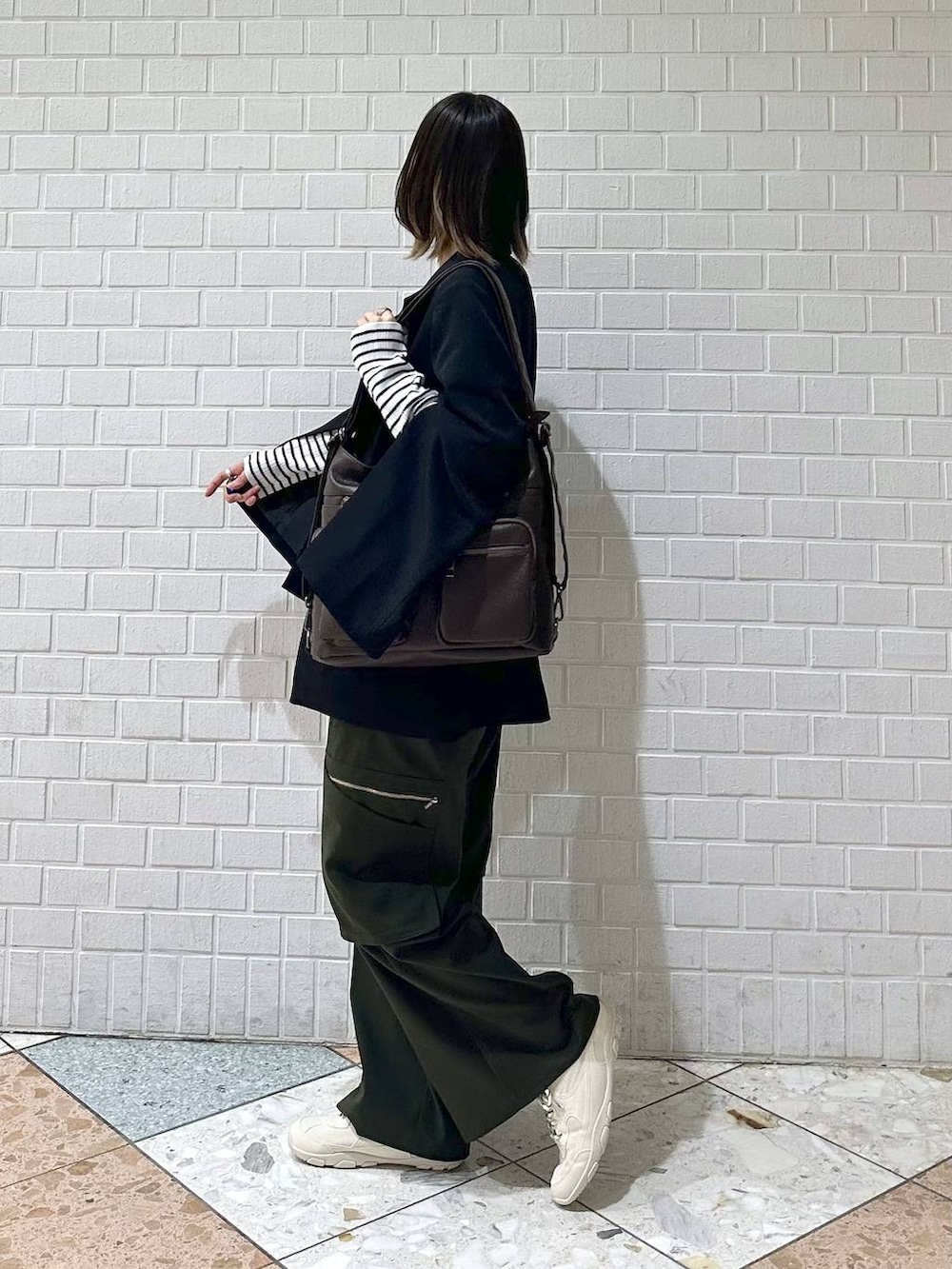 ブラック系のテーラードジャケット、ホワイト系のスニーカー、グリーン系のスラックスを着用したレディースの冬コーディネートの4枚目の写真