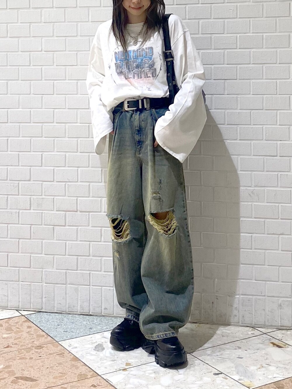 ブラック系のブーツ、ブルー系のデニムパンツ、ブラック系のショルダーバッグを着用したレディースの秋コーディネートの2枚目の写真