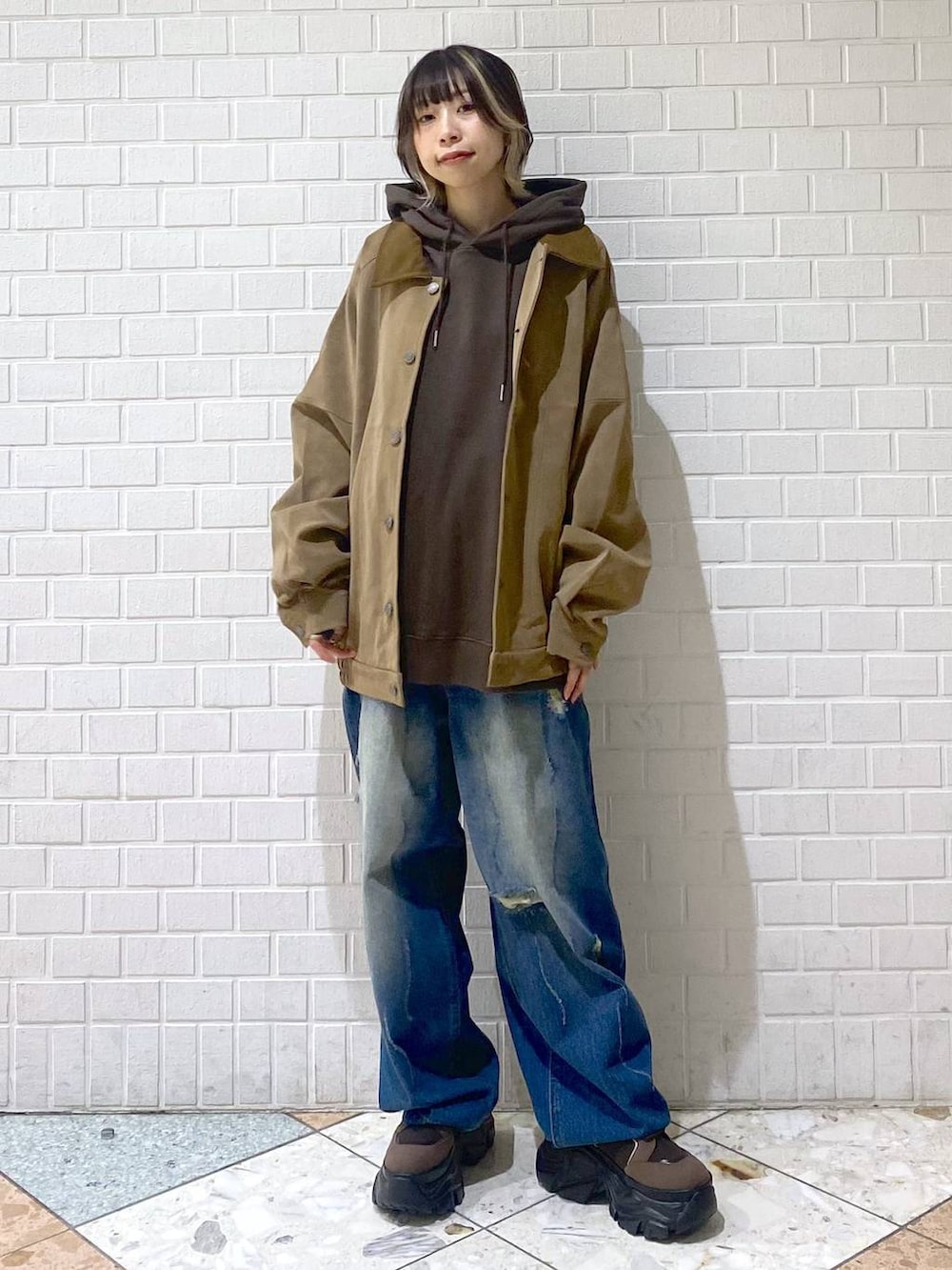 ブラウン系のブーツ、ブルー系のデニムパンツ、ブラウン系のパーカーを着用したレディースの秋コーディネートの2枚目の写真