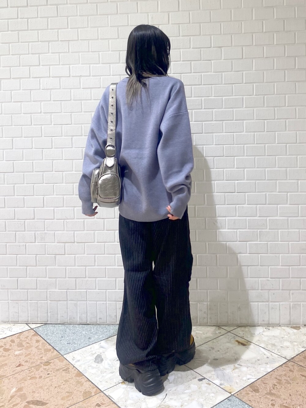 ブラウン系のブーツ、ブラック系のデニムパンツ、シルバー系のショルダーバッグを着用したレディースの冬コーディネートの5枚目の写真