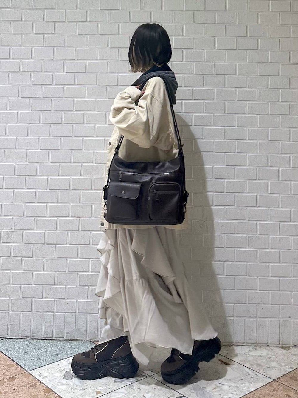 ブラウン系のブーツ、ブラック系のキャミソール、ベージュ系のスカートを着用したレディースの春コーディネートの5枚目の写真