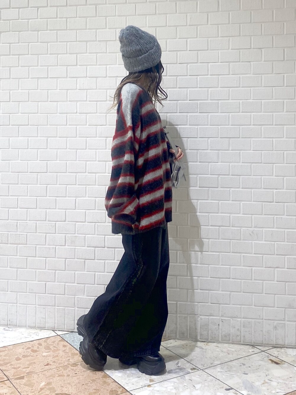 ブラック系のデニムパンツ、ブラック系のブーツ、レッド系のニット/セーターを着用したレディースの秋コーディネートの5枚目の写真