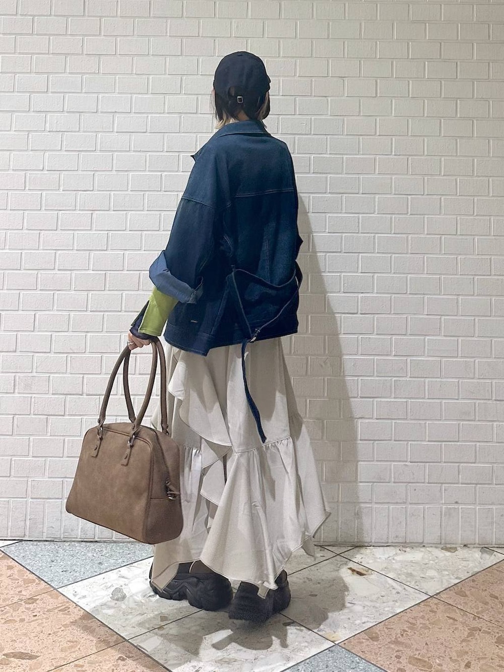 ブラウン系のブーツ、イエロー系のボストンバッグ、ベージュ系のスカートを着用したレディースの冬コーディネートの6枚目の写真