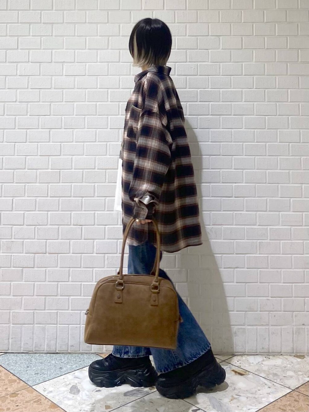 ブラック系のスニーカー、イエロー系のボストンバッグ、ブルー系のデニムパンツを着用したレディースの秋コーディネートの4枚目の写真