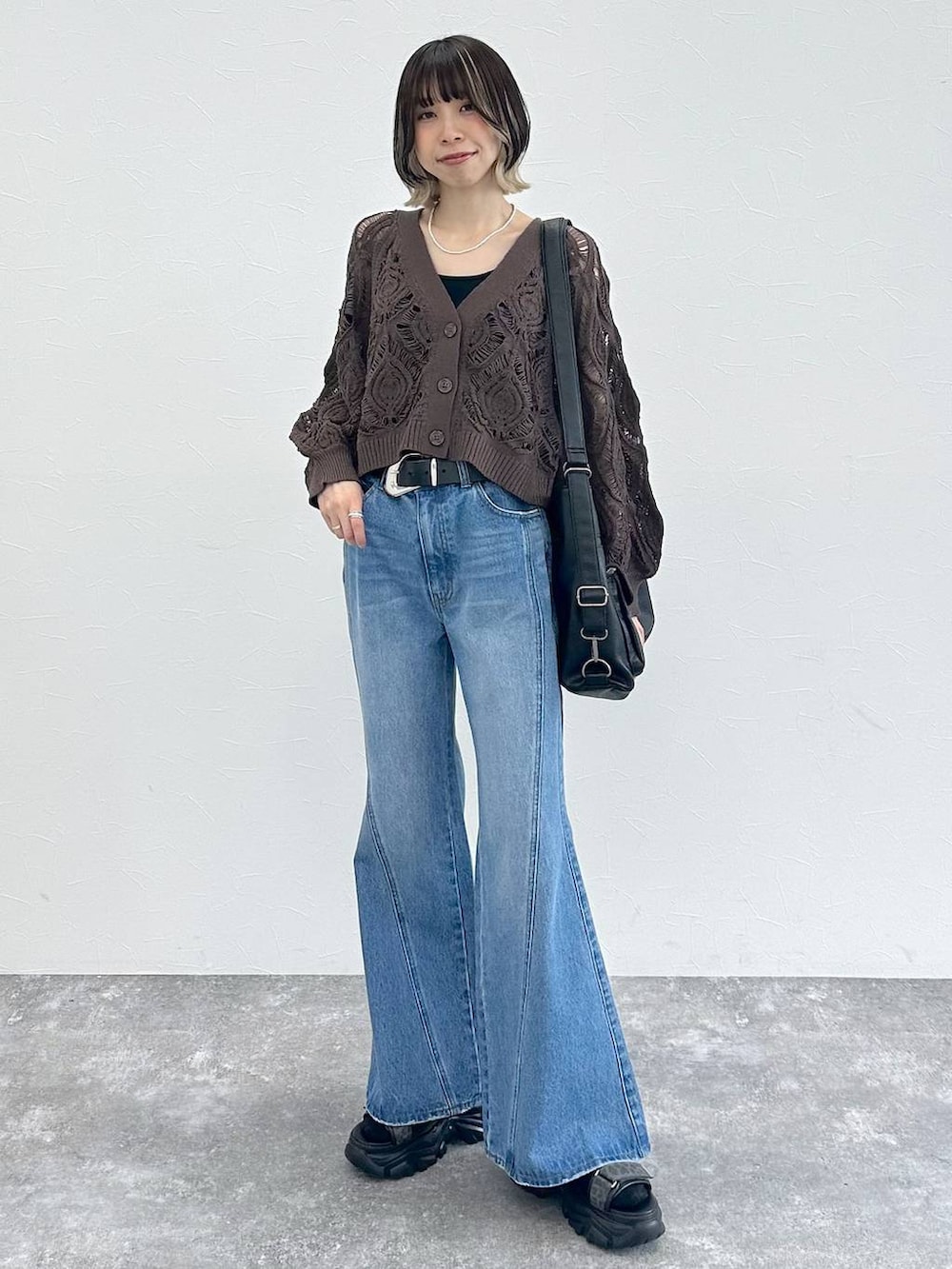 ブラック系のキャミソール、ブラウン系のカーディガン/ボレロ、ブルー系のデニムパンツを着用したレディースの春コーディネートの4枚目の写真