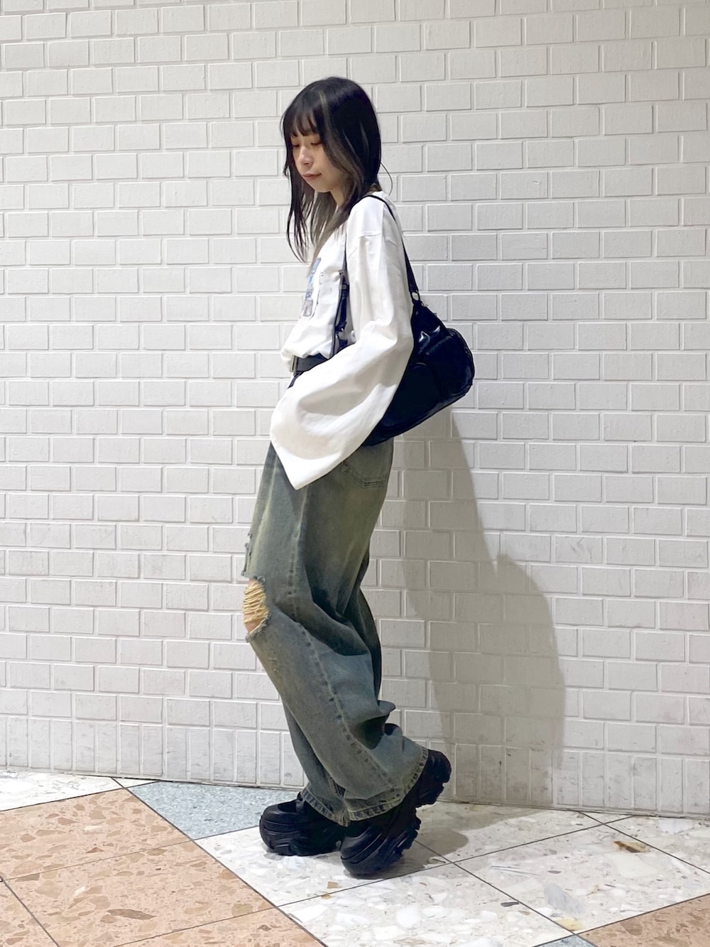 ブラック系のブーツ、ブルー系のデニムパンツ、ブラック系のショルダーバッグを着用したレディースの秋コーディネートの3枚目の写真