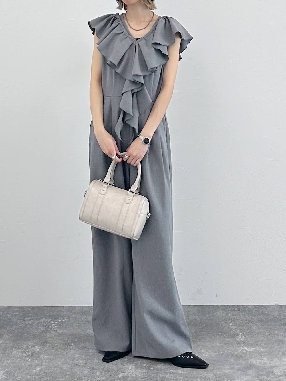 ホワイト系のボストンバッグ、ブラック系のサンダル、グレー系のサロペット/オーバーオールを着用したレディースの春コーディネートの3枚目の写真