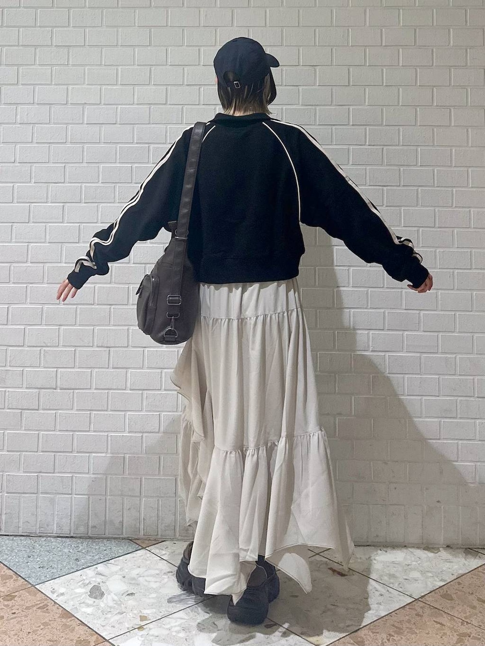 ブラウン系のブーツ、ブラック系のキャミソール、ベージュ系のスカートを着用したレディースの春コーディネートの6枚目の写真