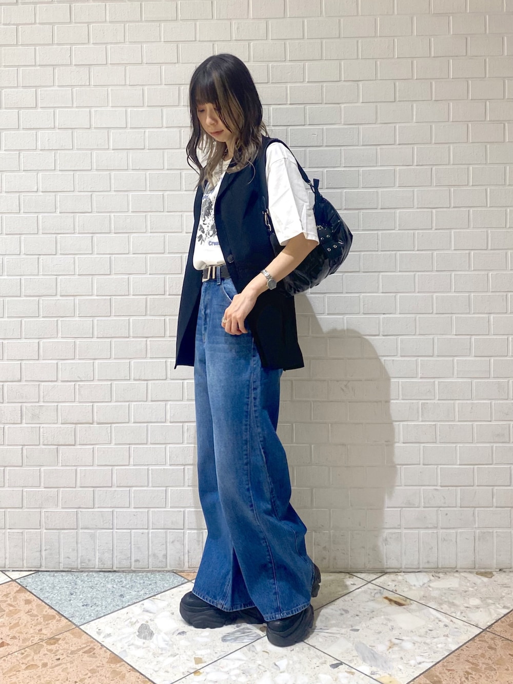 ブルー系のデニムパンツ、ブラック系のスニーカー、ブラック系のショルダーバッグを着用したレディースの秋コーディネートの2枚目の写真