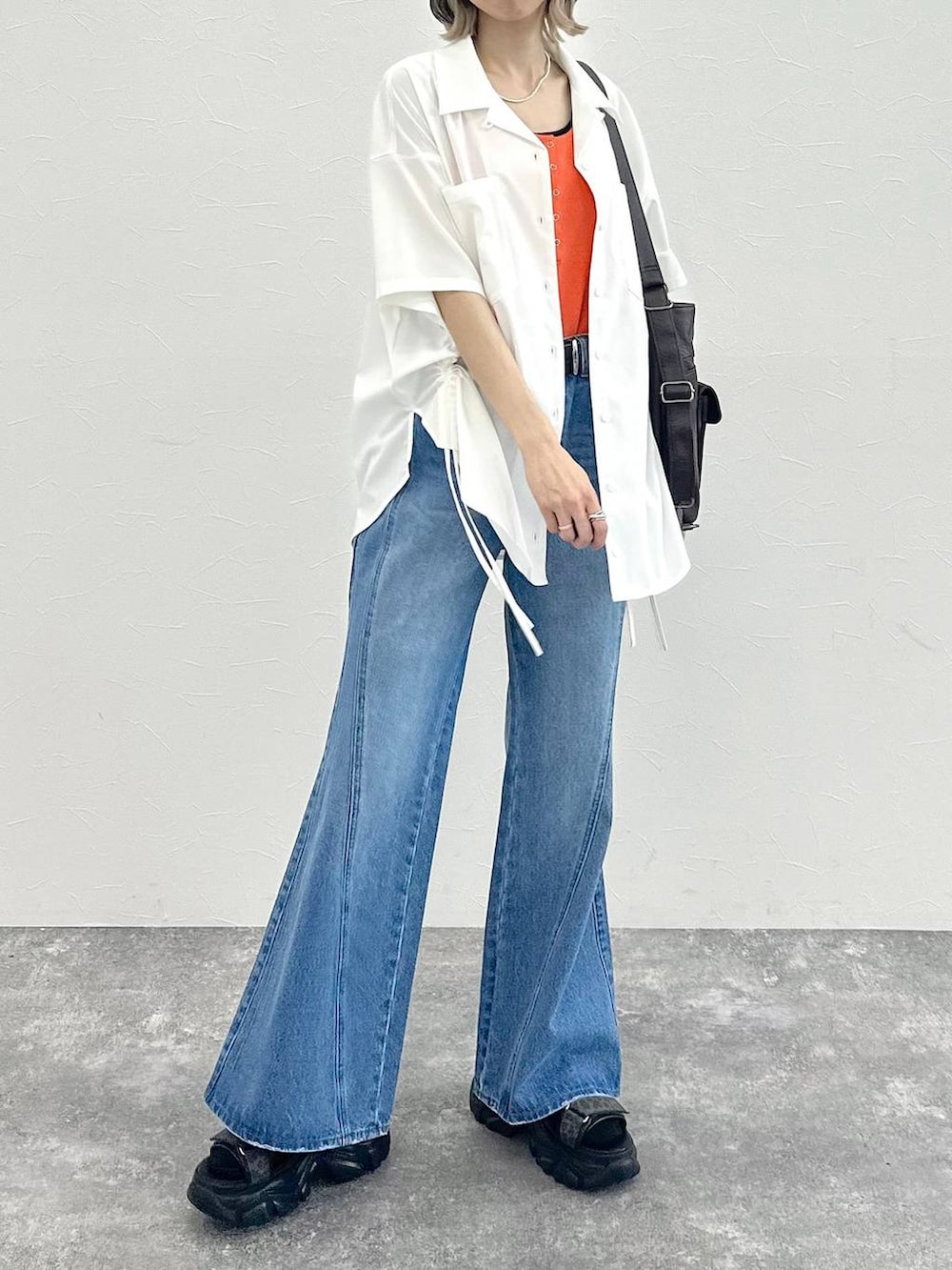 ブルー系のデニムパンツ、ブラック系のショルダーバッグ、グレー系のサンダルを着用したレディースの春コーディネートの4枚目の写真