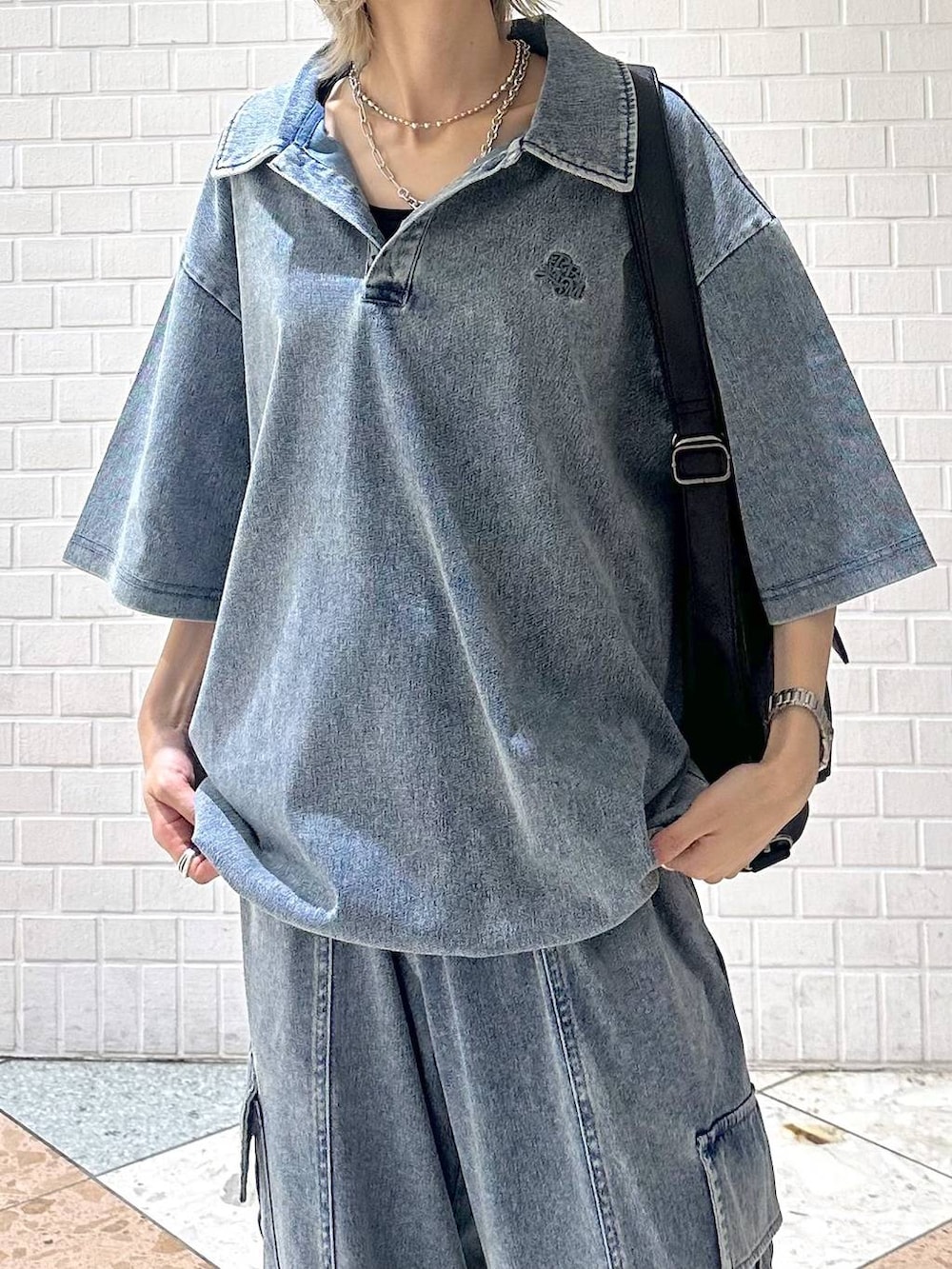 ブラック系のスニーカー、ブラック系のショルダーバッグ、ブルー系のポロシャツを着用したレディースの夏コーディネートの7枚目の写真