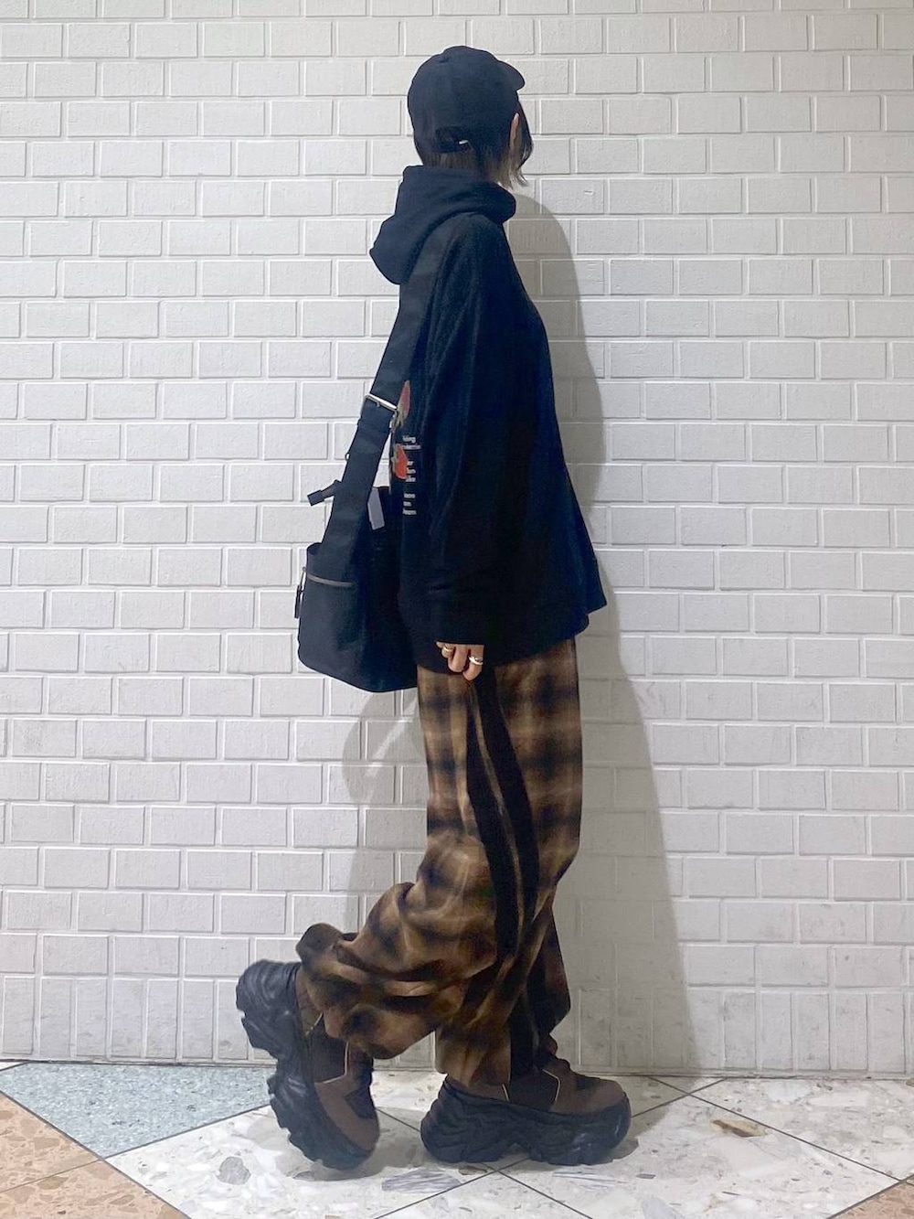 ブラウン系のブーツ、ブラック系のボストンバッグ、ブラック系のパーカーを着用したレディースの秋コーディネートの7枚目の写真