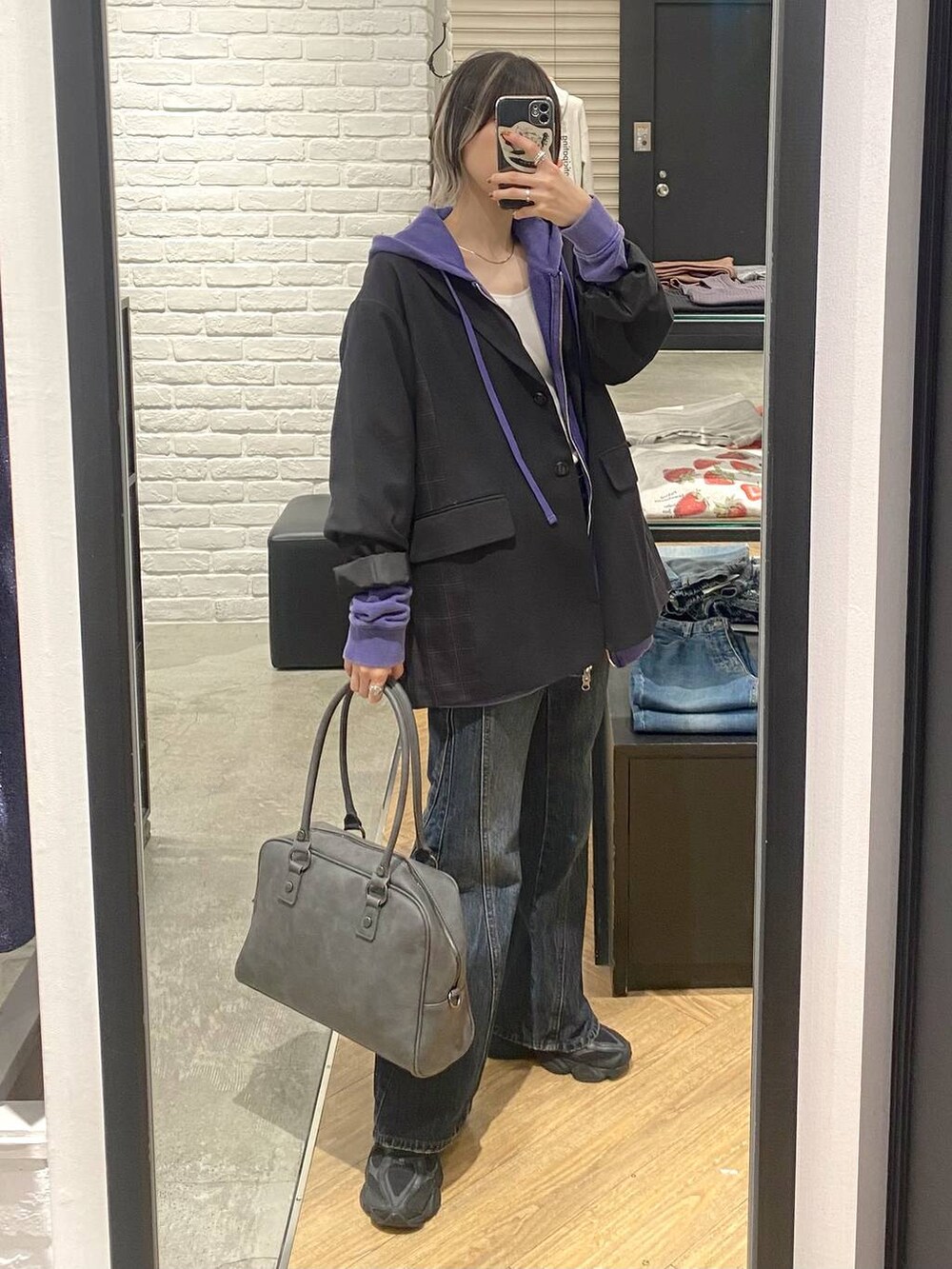 グレー系のボストンバッグ、ブルー系のデニムパンツ、ブラック系のテーラードジャケットを着用したレディースの秋コーディネートの3枚目の写真