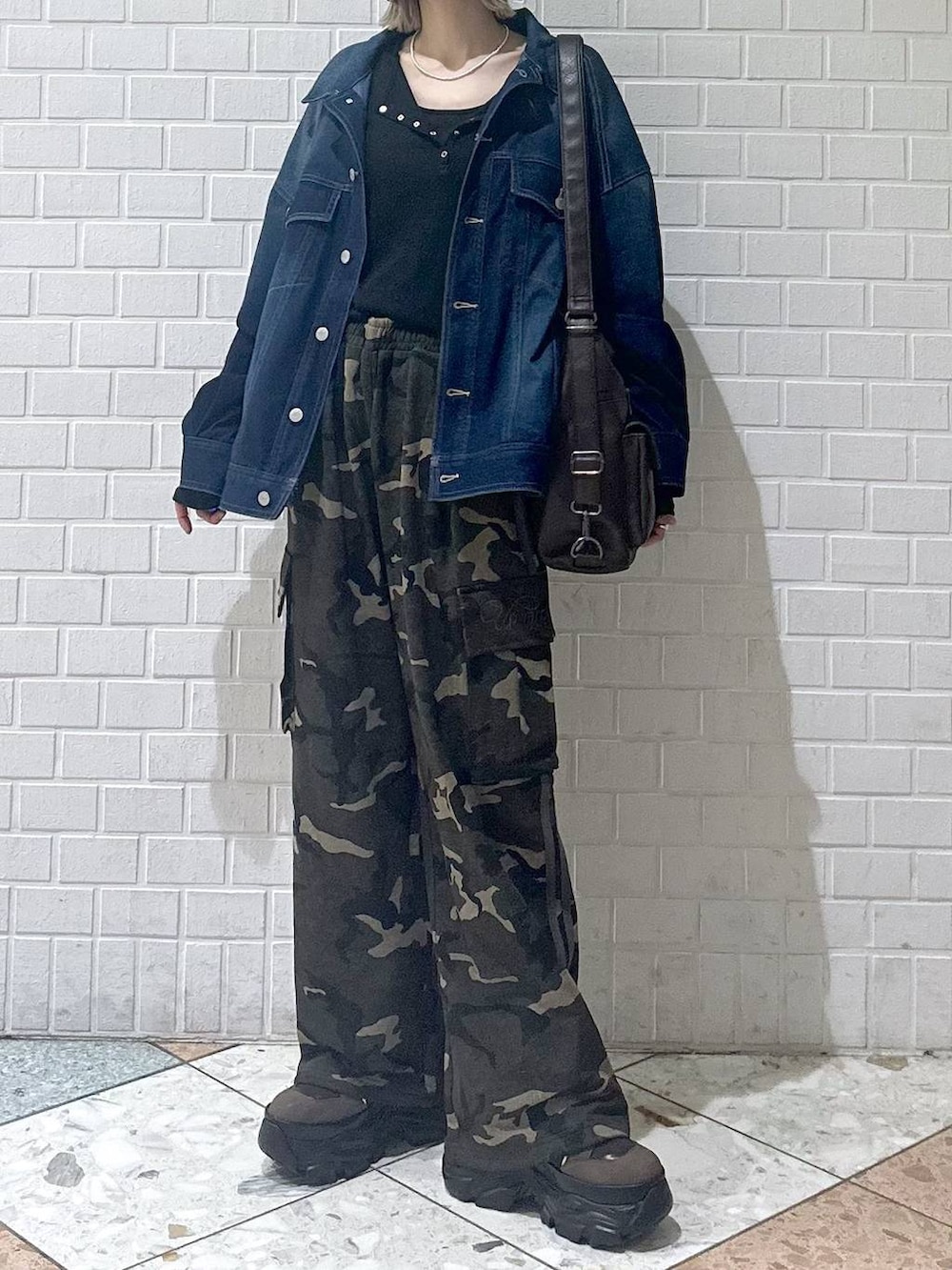 ブラウン系のブーツ、ブラック系のキャミソール、ブルー系のブルゾンを着用したレディースの春コーディネートの2枚目の写真