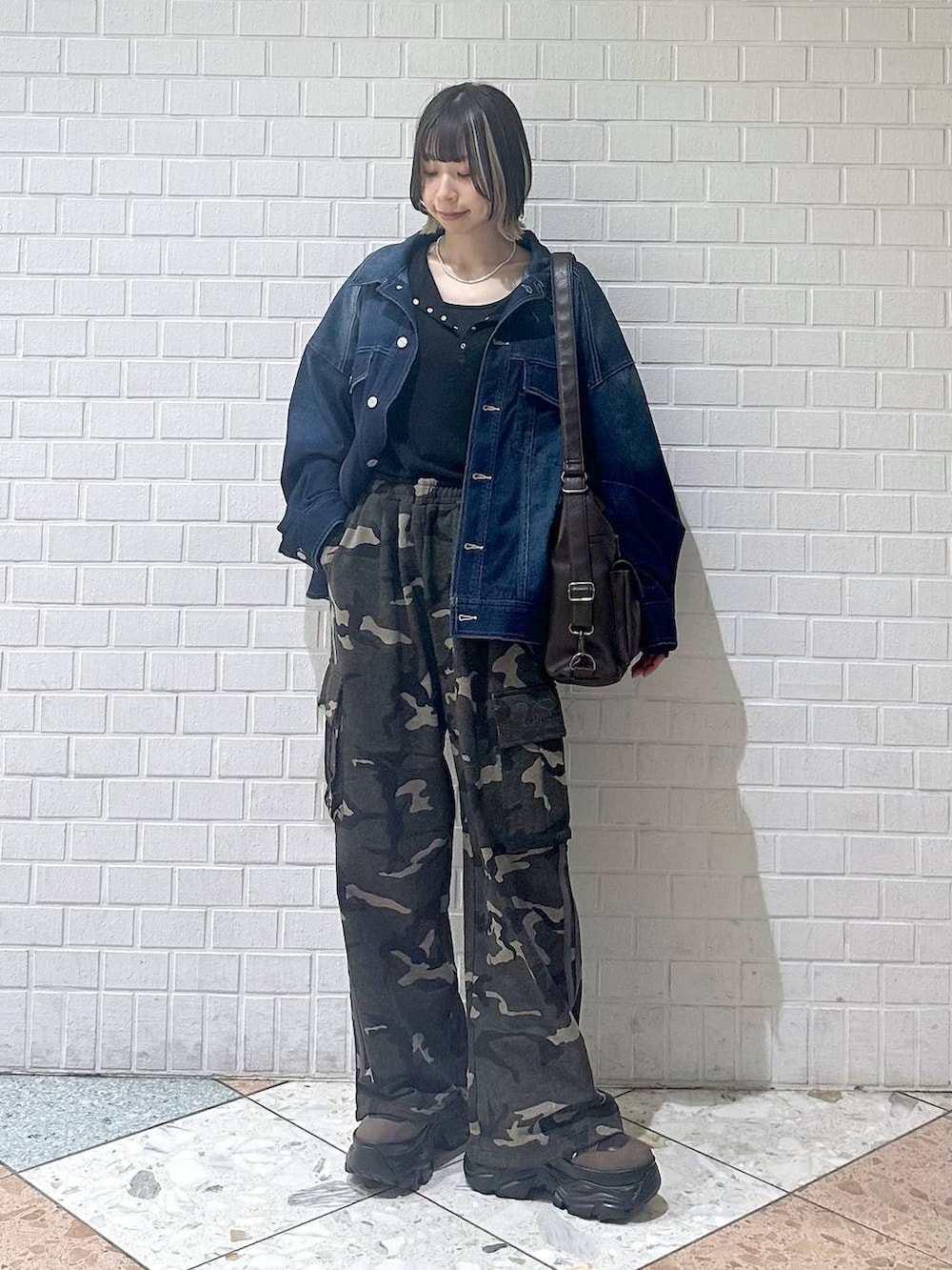 ブラウン系のブーツ、ブラック系のキャミソール、ブルー系のブルゾンを着用したレディースの春コーディネートの3枚目の写真