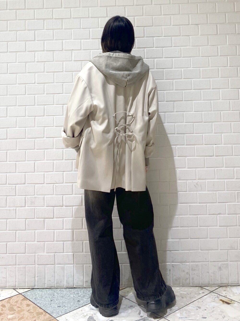 ブラック系のデニムパンツ、ベージュ系のテーラードジャケット、グレー系のパーカーを着用したレディースの冬コーディネートの4枚目の写真