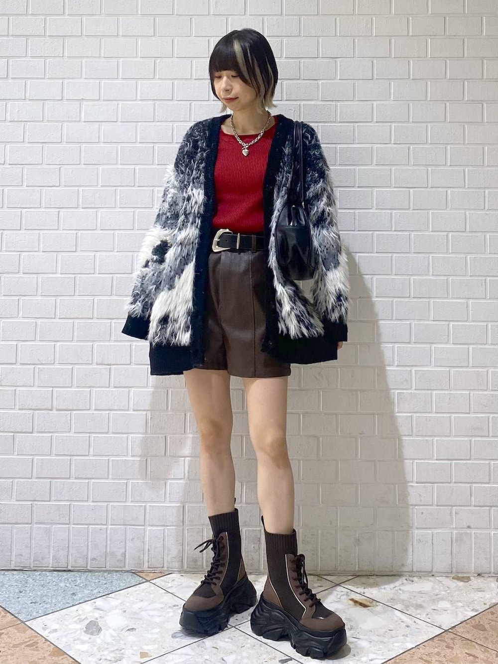 ブラウン系のブーツ、ブラック系のボストンバッグ、レッド系のニット/セーターを着用したレディースの秋コーディネートの3枚目の写真