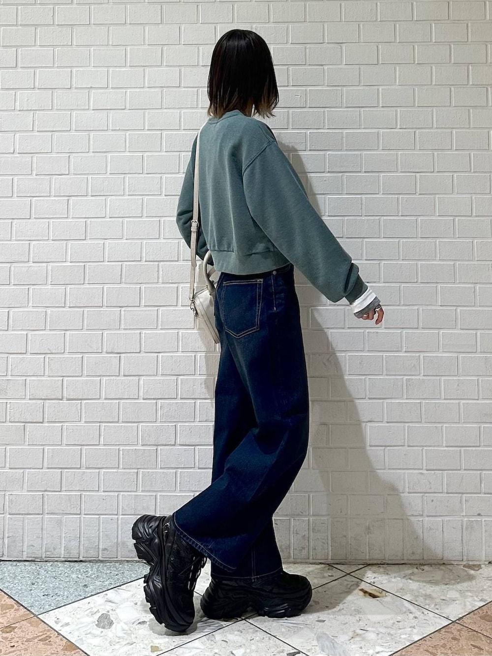 ブラック系のスニーカー、ブルー系のスラックス、ホワイト系のボストンバッグを着用したレディースの冬コーディネートの7枚目の写真