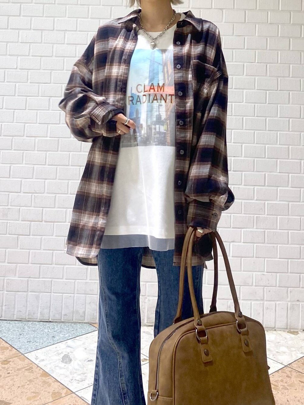 ブラック系のスニーカー、イエロー系のボストンバッグ、ブルー系のデニムパンツを着用したレディースの秋コーディネートの7枚目の写真