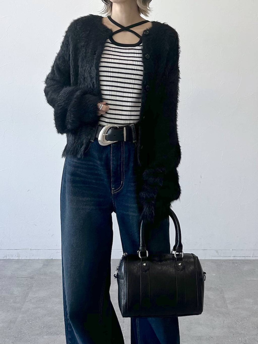 ブラック系のブーツ、ブルー系のスラックス、ブラック系のボストンバッグを着用したレディースの冬コーディネートの8枚目の写真