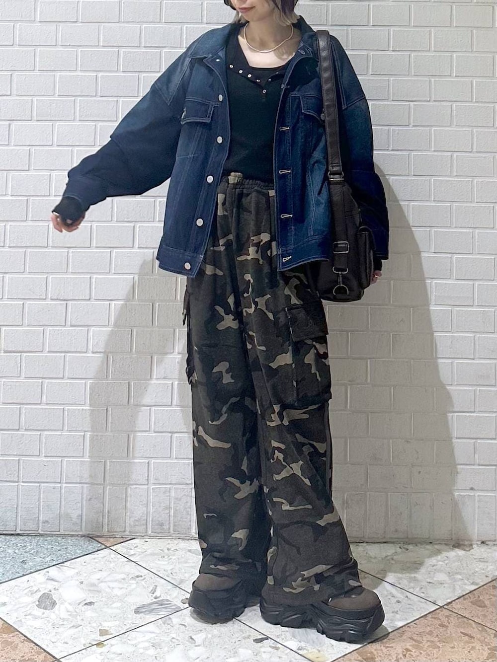 ブラウン系のブーツ、ブラック系のキャミソール、ブルー系のブルゾンを着用したレディースの春コーディネートの4枚目の写真