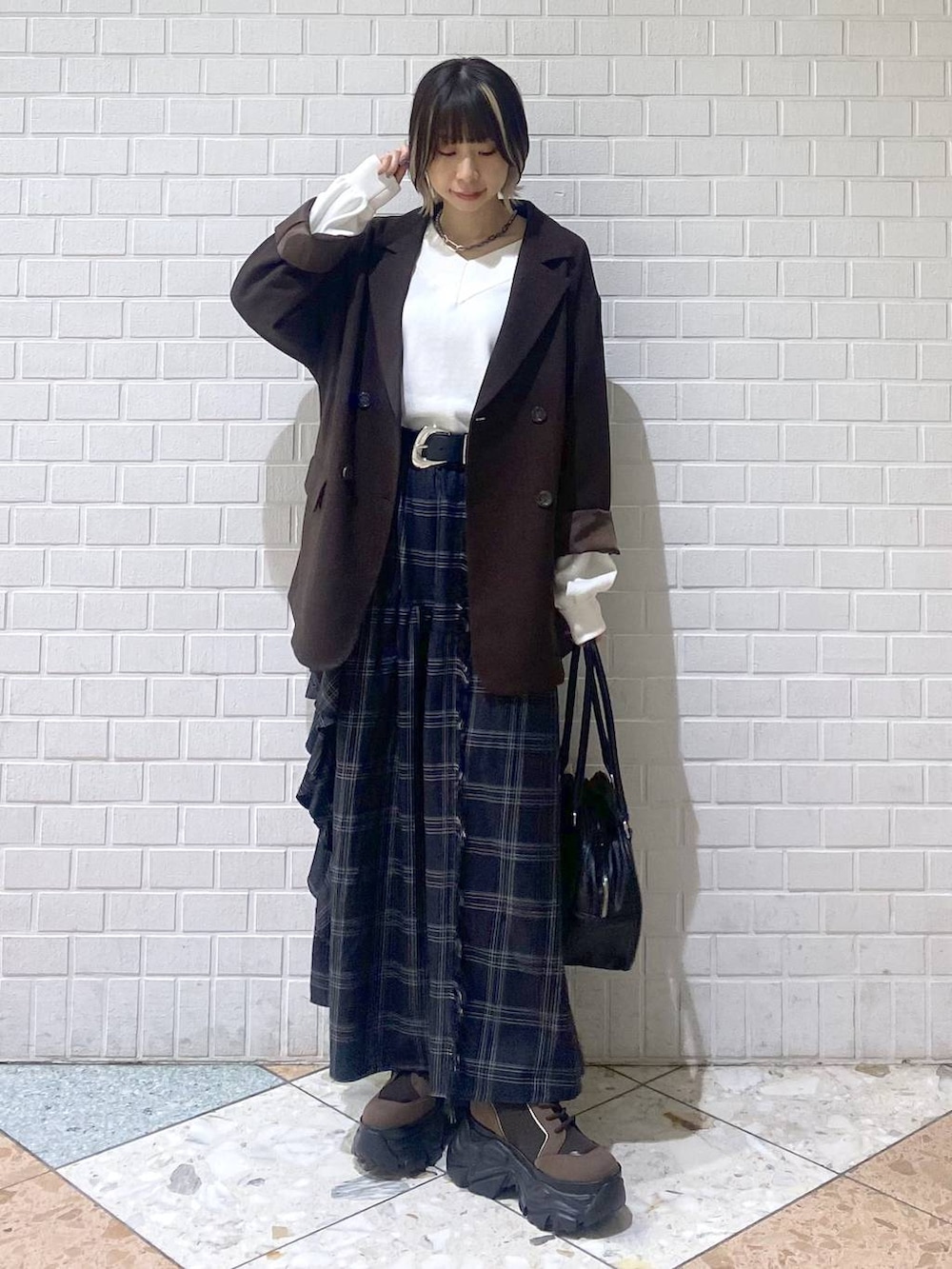 ブラウン系のブーツ、ブラック系のボストンバッグ、ホワイト系のニット/セーターを着用したレディースの秋コーディネートの3枚目の写真