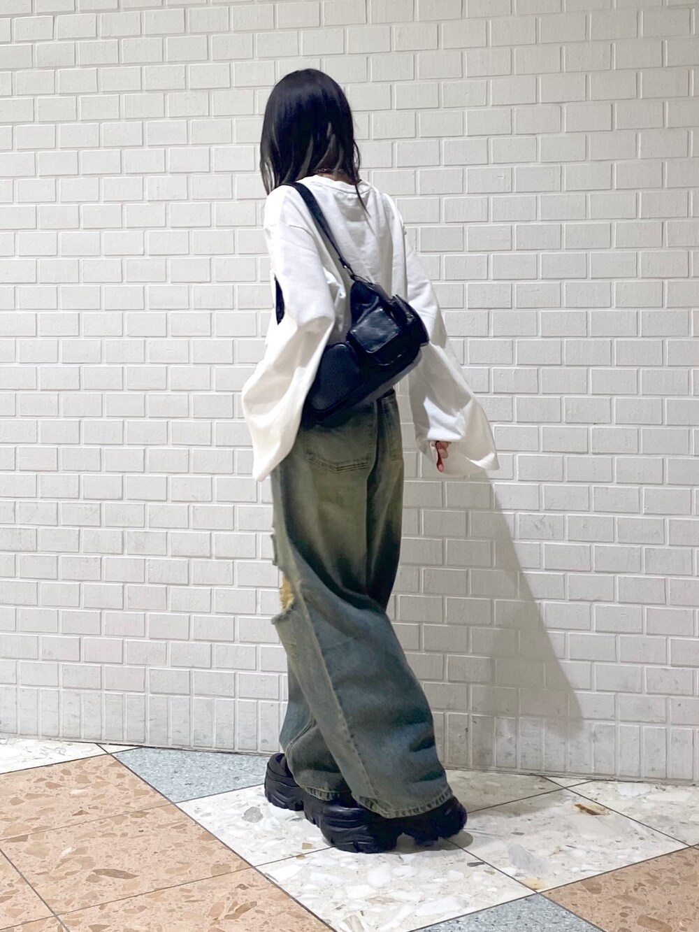 ブラック系のブーツ、ブルー系のデニムパンツ、ブラック系のショルダーバッグを着用したレディースの秋コーディネートの4枚目の写真