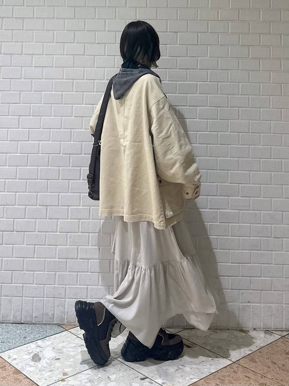 ブラウン系のブーツ、ブラック系のキャミソール、ベージュ系のスカートを着用したレディースの春コーディネートの7枚目の写真