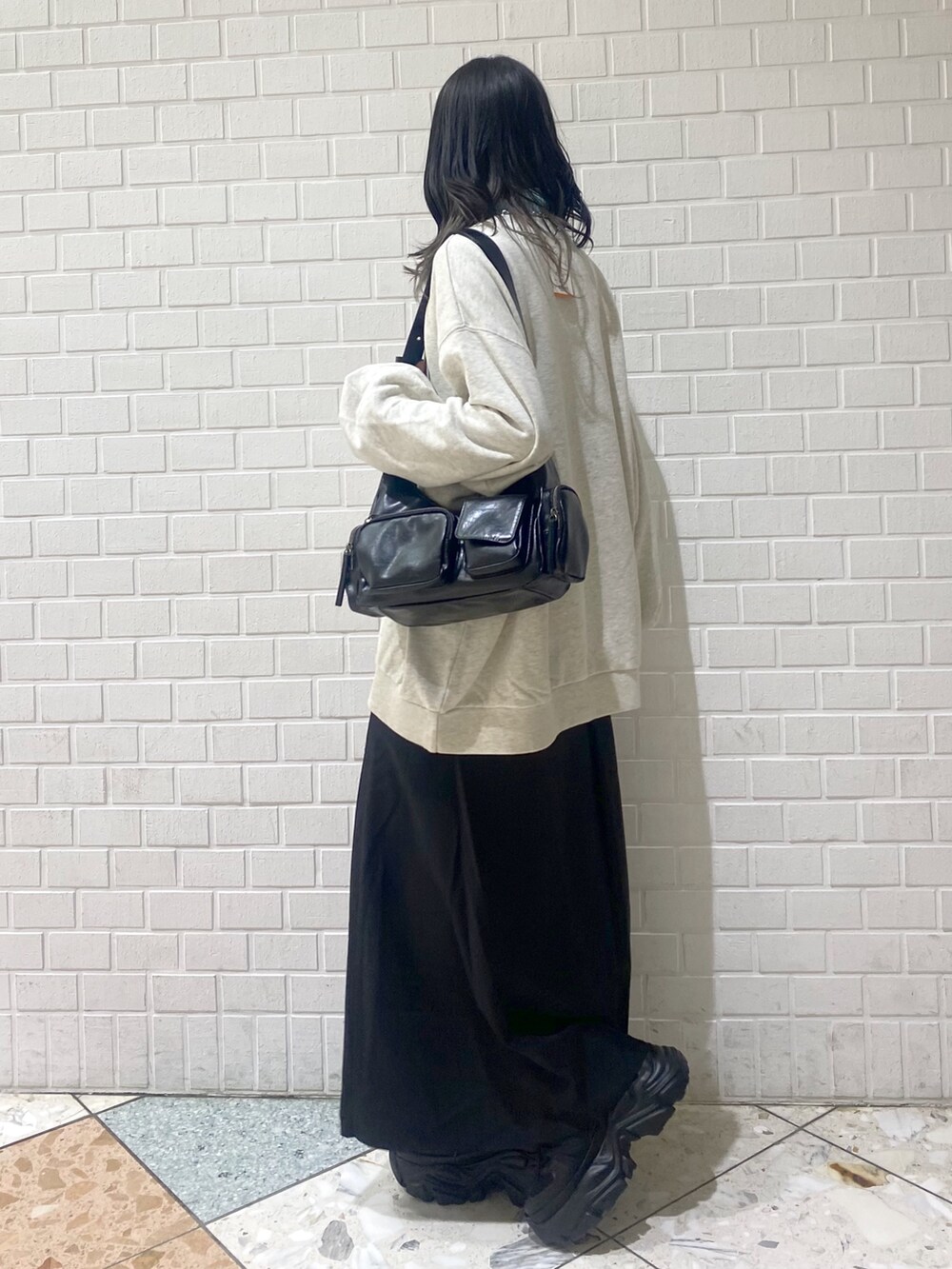 ブラック系のスニーカー、ブラック系のスカート、ベージュ系のスウェットを着用したレディースの冬コーディネートの2枚目の写真