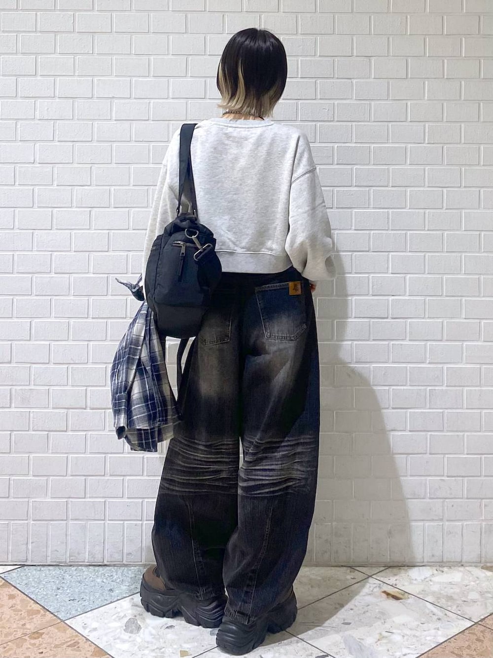 ブラウン系のブーツ、ブラック系のボストンバッグ、ブラック系のデニムパンツを着用したレディースの秋コーディネートの5枚目の写真