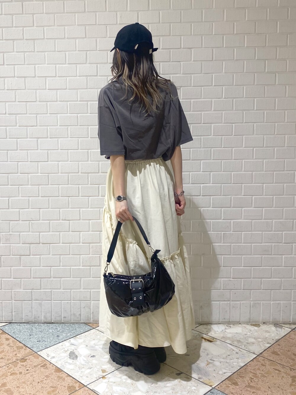 ブラック系のショルダーバッグ、ブラック系のスニーカー、ホワイト系のスカートを着用したレディースの夏コーディネートの4枚目の写真