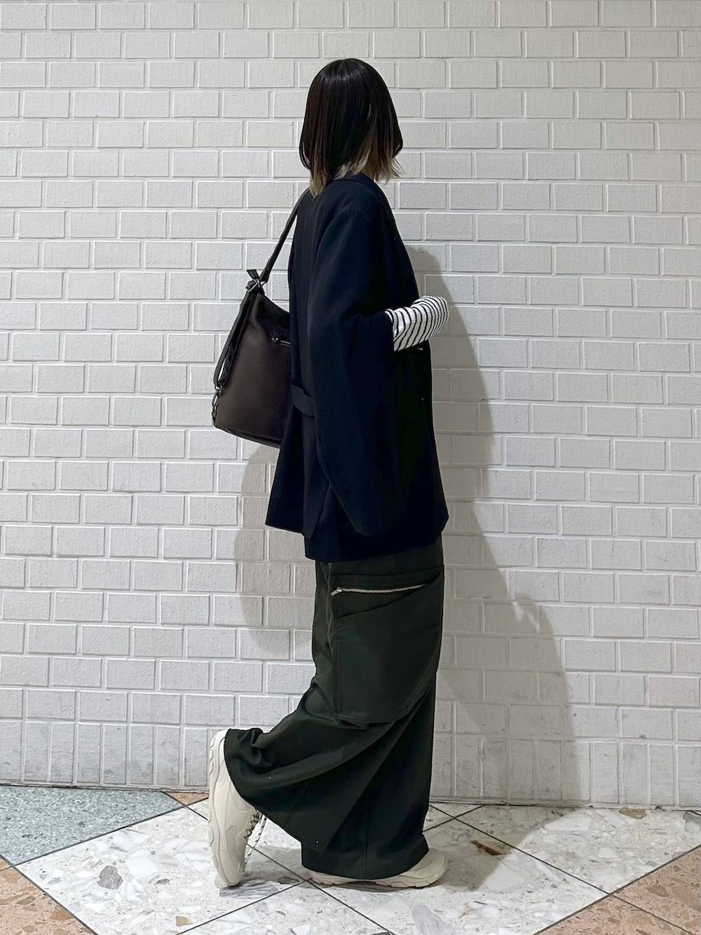 ブラック系のテーラードジャケット、ホワイト系のスニーカー、グリーン系のスラックスを着用したレディースの冬コーディネートの7枚目の写真