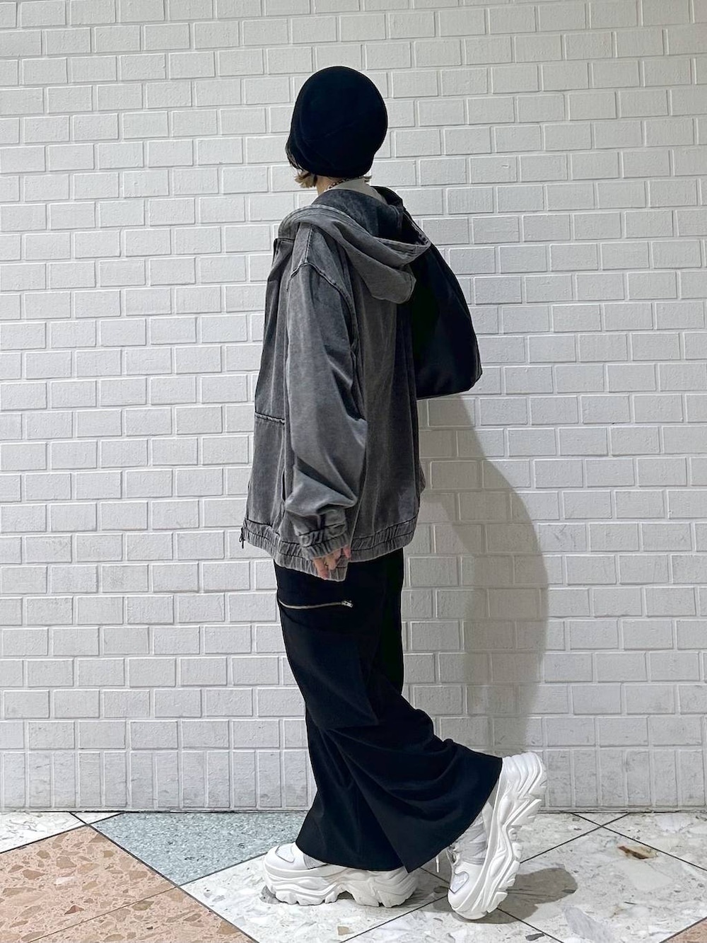 ホワイト系のスニーカー、ブラック系のスラックス、ブラック系のパーカーを着用したレディースの春コーディネートの6枚目の写真